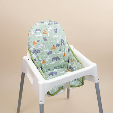 High chair with a green cushion featuring animal patterns on a beige background