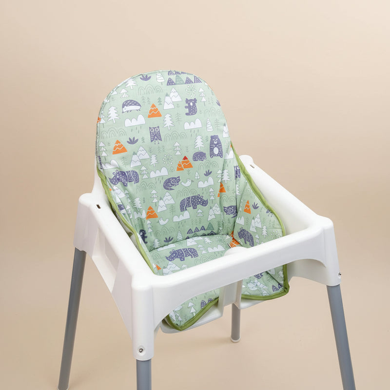 High chair with a green cushion featuring animal patterns on a beige background