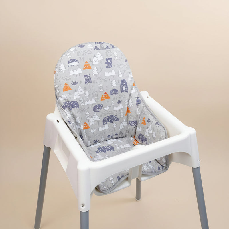 White high chair with a grey patterned cover on a beige background