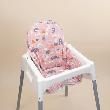 White high chair with a pink patterned cover on a beige background