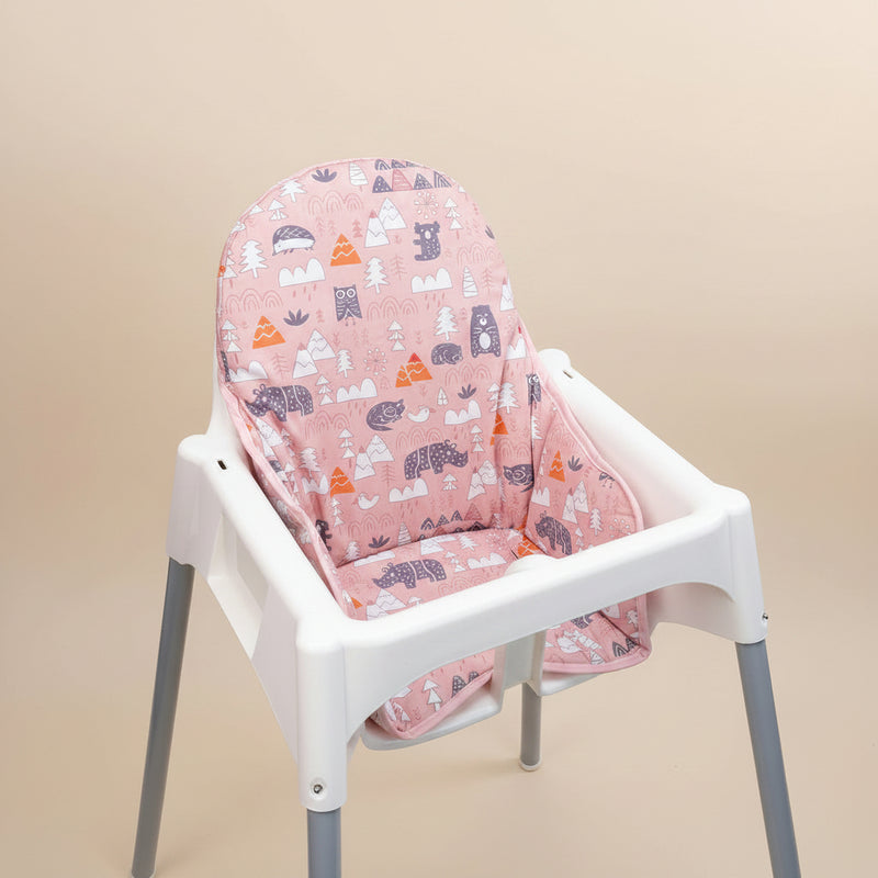White high chair with a pink patterned cover on a beige background