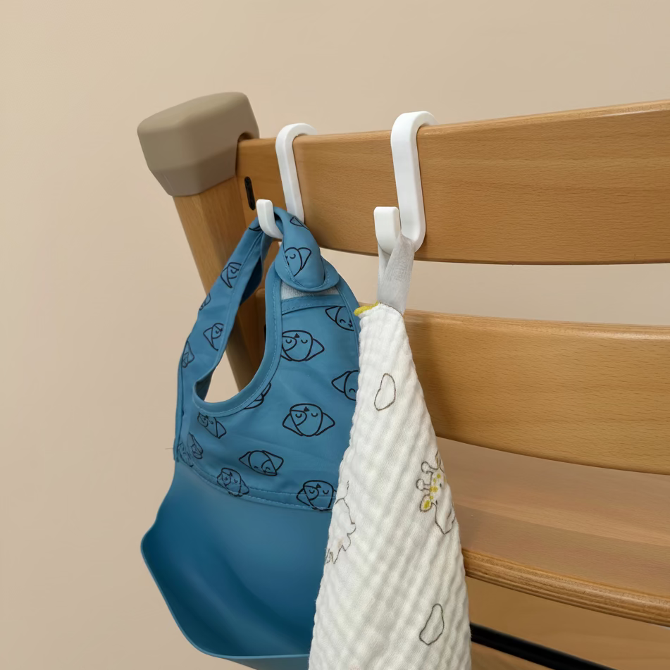 Blue baby bib and white towel hanging on a wooden chair with a beige background