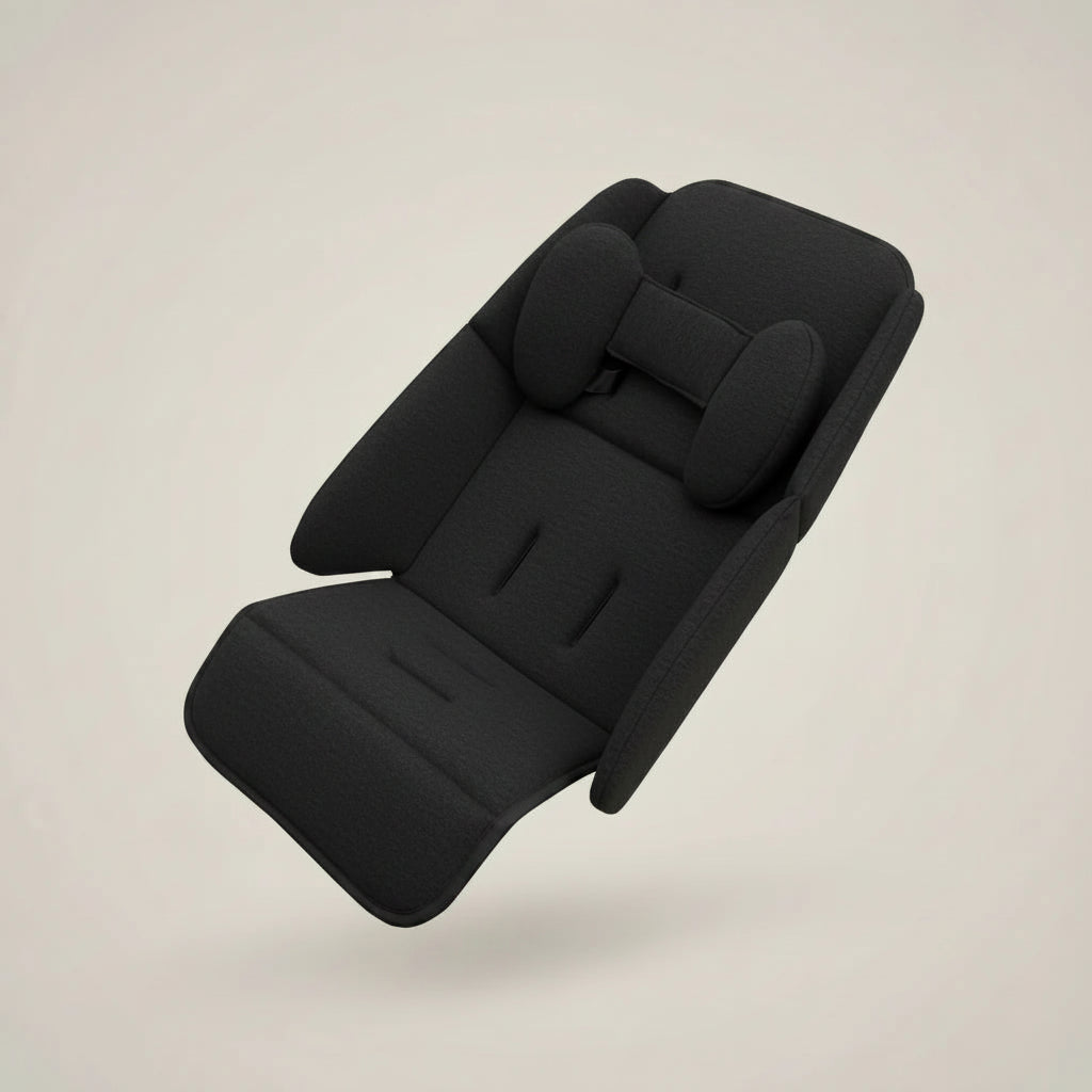 A black fabric car seat cushion with integrated headrest and side bolsters, shown floating against a plain warm beige background.