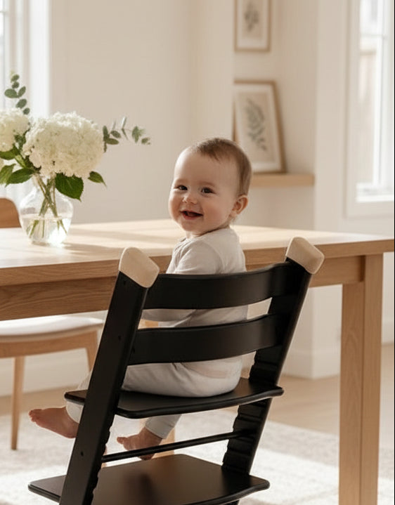 Child sitting in a black high chair in a living room