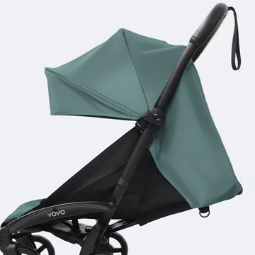 A close-up of a Yoyo baby stroller with a aqua canopy and black frame, set against a plain light gray background.