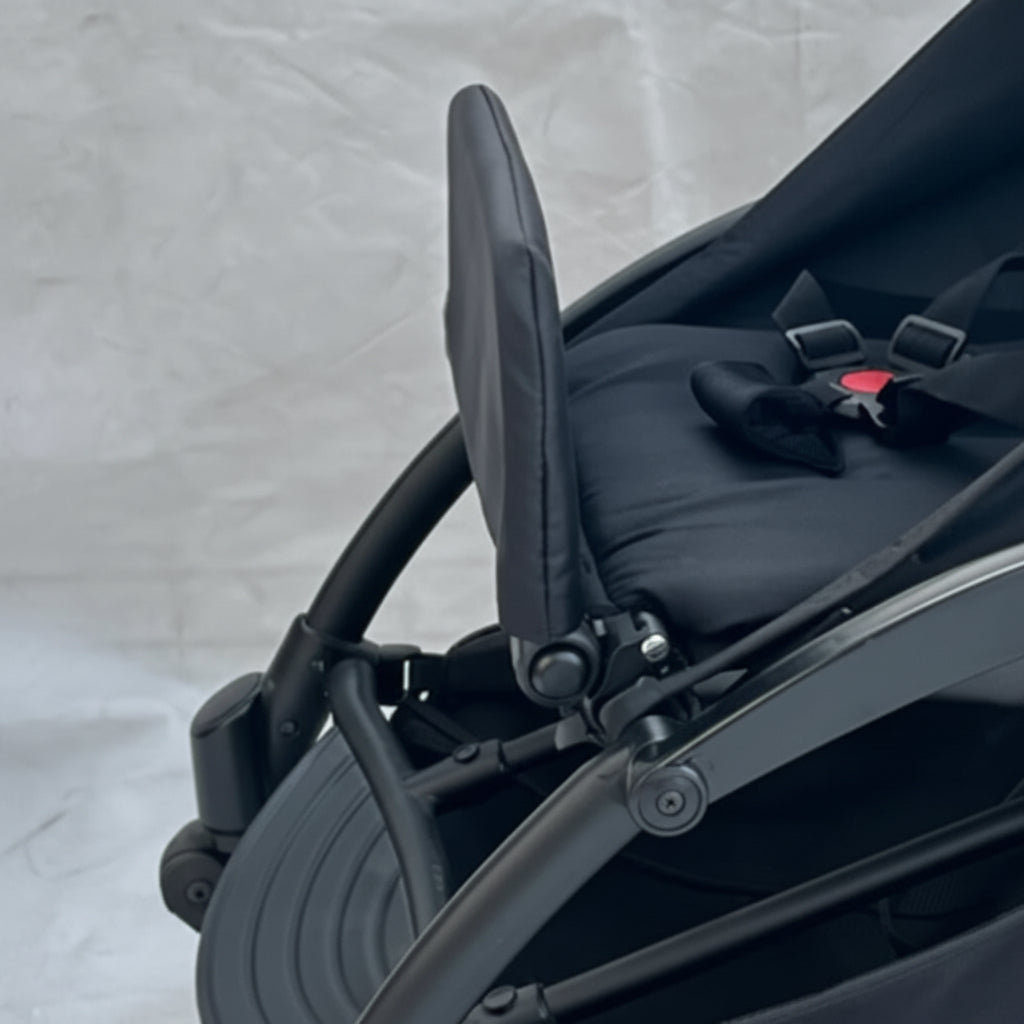Close-up of a black stroller with a bow detail on a light gray background