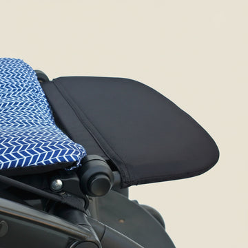 Close-up of a black stroller leg rest with a blue and white patterned cover on a white background