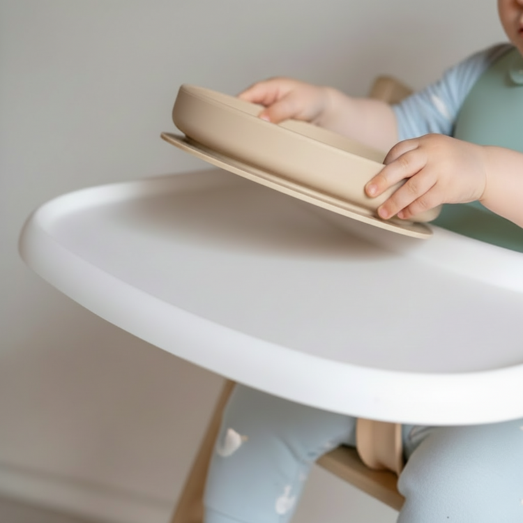 Child using a tray on a high chair with a neutral background